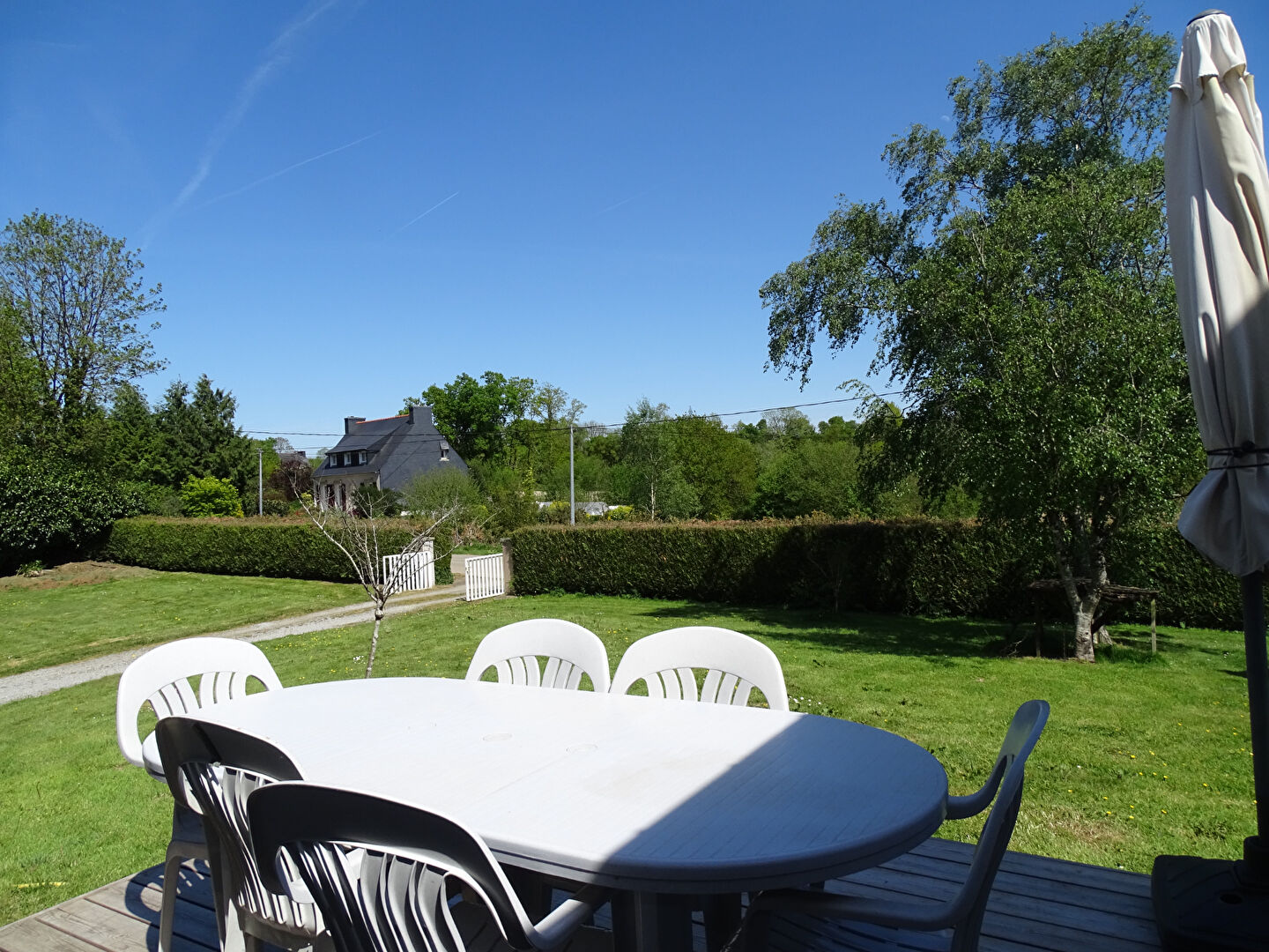 Spacious garden with outdoor dining area, view of a property in Finistère, Brittany, surrounded by greenery.