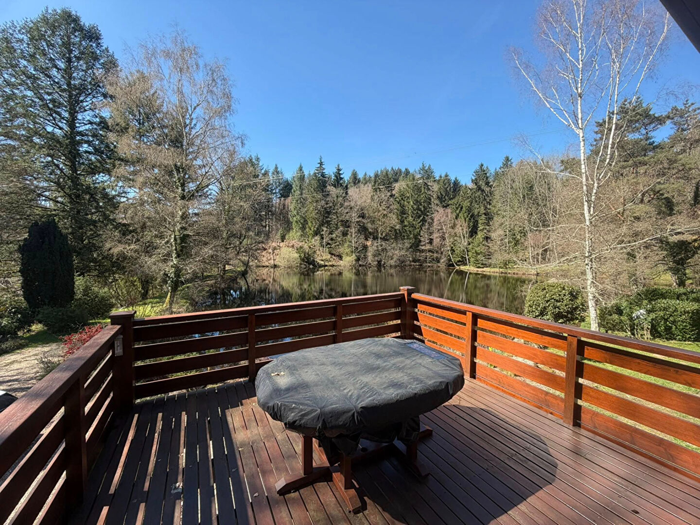 Deck overlooking a tranquil lake surrounded by trees in Haute-Vienne, Nouvelle-Aquitaine. Ideal for relaxation.