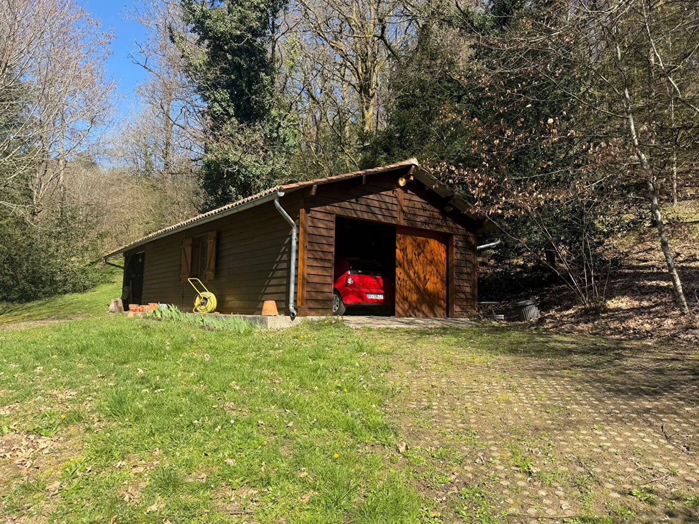 Wooden property with garage, situated in Haute-Vienne, Nouvelle-Aquitaine, surrounded by trees and greenery.