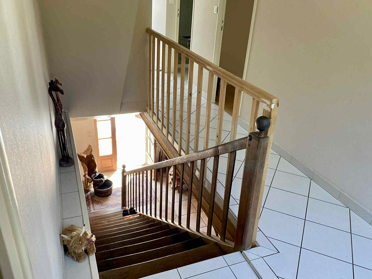 Spacious property in Charente featuring a wooden staircase and tiled flooring, enhancing natural light throughout.
