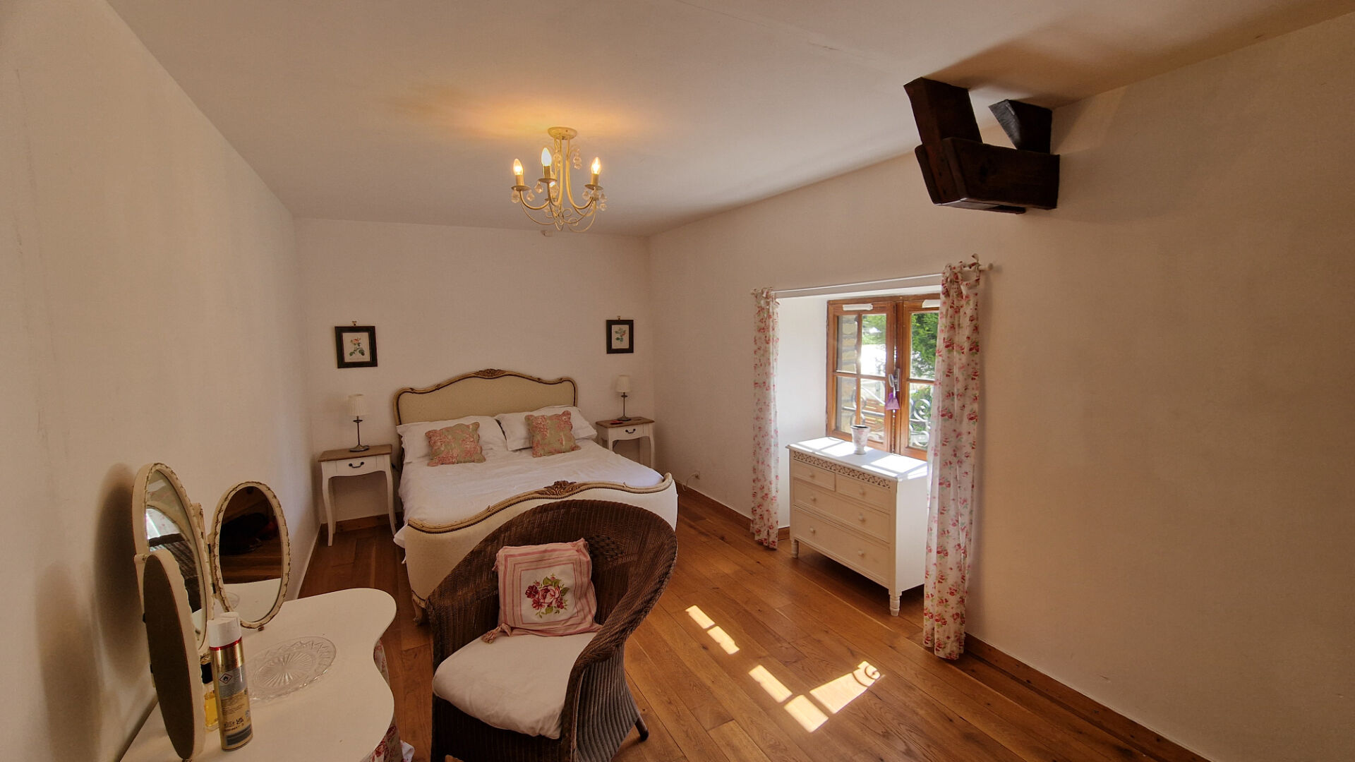 Bright bedroom with wooden flooring, large wardrobe, and window in a property located in Morbihan, Brittany.