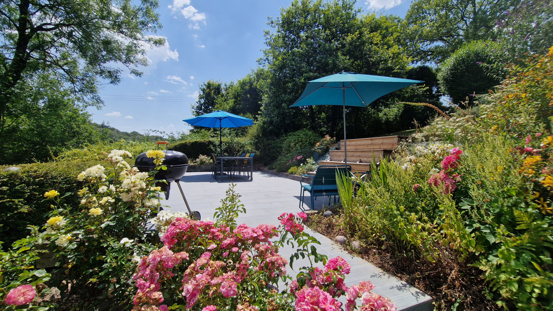 Spacious property in Côtes-d'Armor with a landscaped garden, outdoor seating, and vibrant flowerbeds.