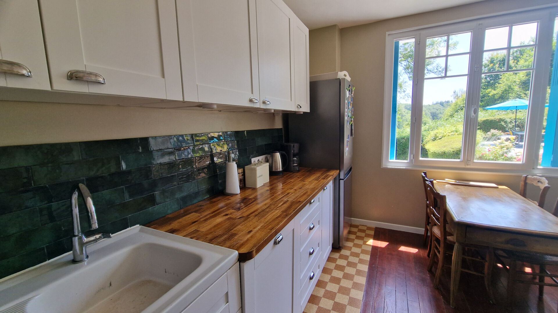 Modern property kitchen with wooden worktop, green tile splashback, and views of the garden in Côtes-d'Armor, Brittany.