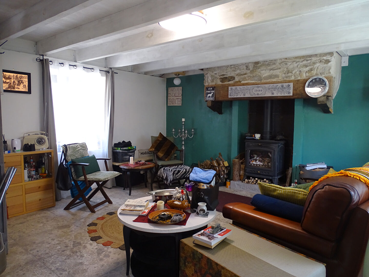 Cosy property in Finistère, Brittany, featuring a lounge with a fireplace, wooden beams, and eclectic furnishings.