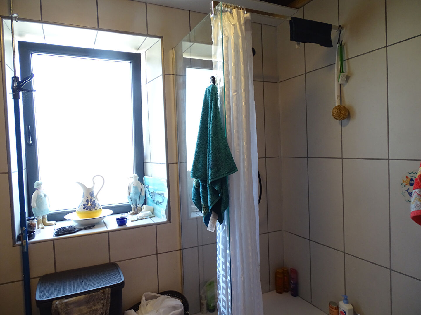 Shower area in a property located in Finistère, Brittany, featuring tiled walls and natural light.