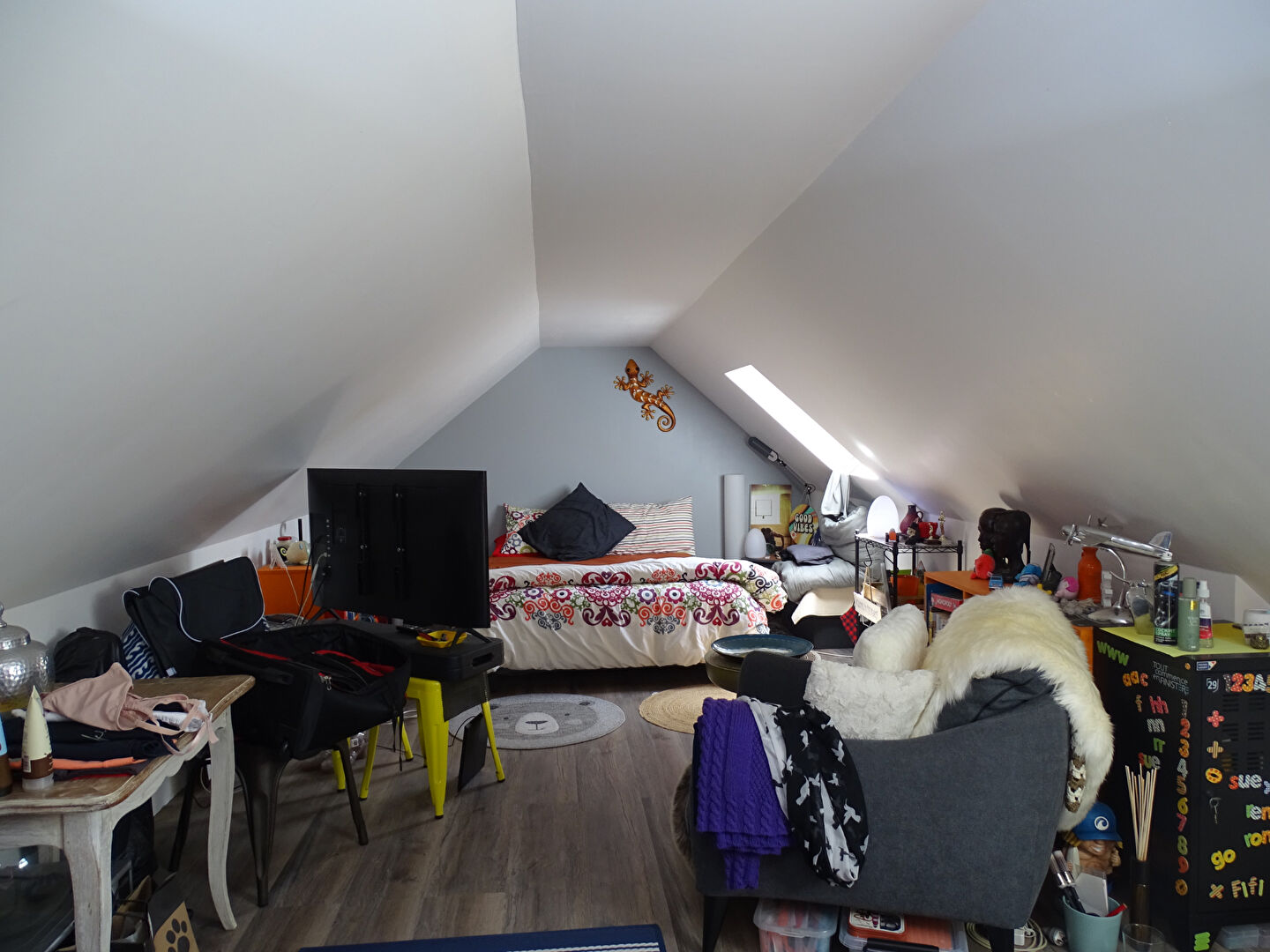 Spacious property in Finistère, Brittany featuring a bright attic bedroom with sloped ceilings and cosy furnishings.