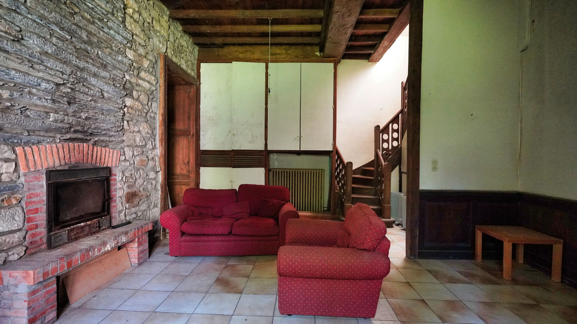 Spacious property with stone features, red sofas, and staircase, located in Morbihan, Brittany, 56200.