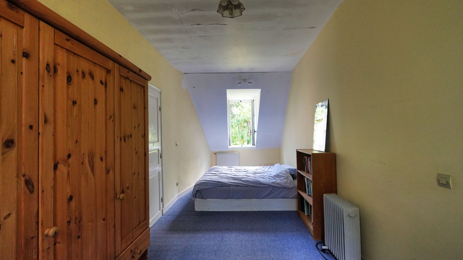 Spacious bedroom in a property located in Morbihan, Brittany, featuring a bed, wardrobe, and natural light from the window.
