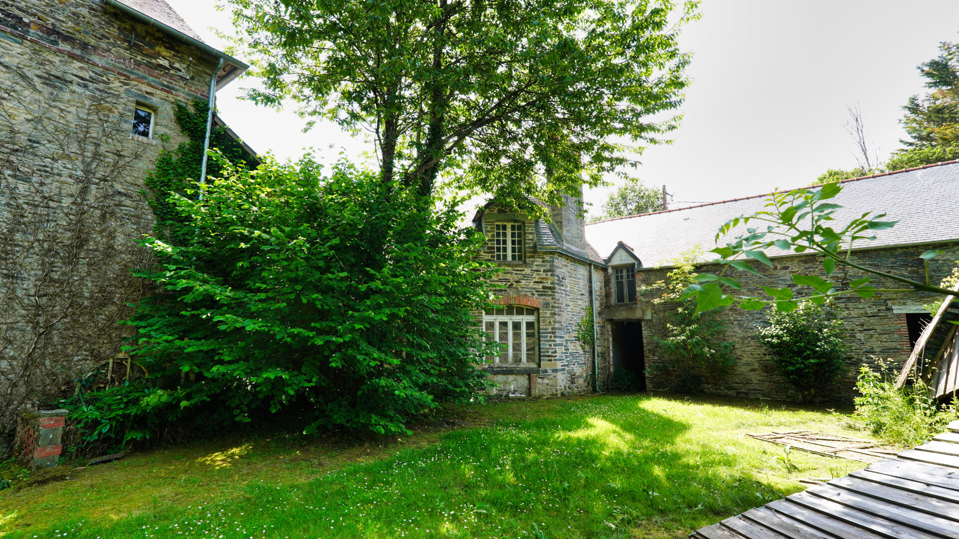 Five-bedroom property in Morbihan, Brittany, featuring a spacious garden and stone architecture surrounded by greenery.