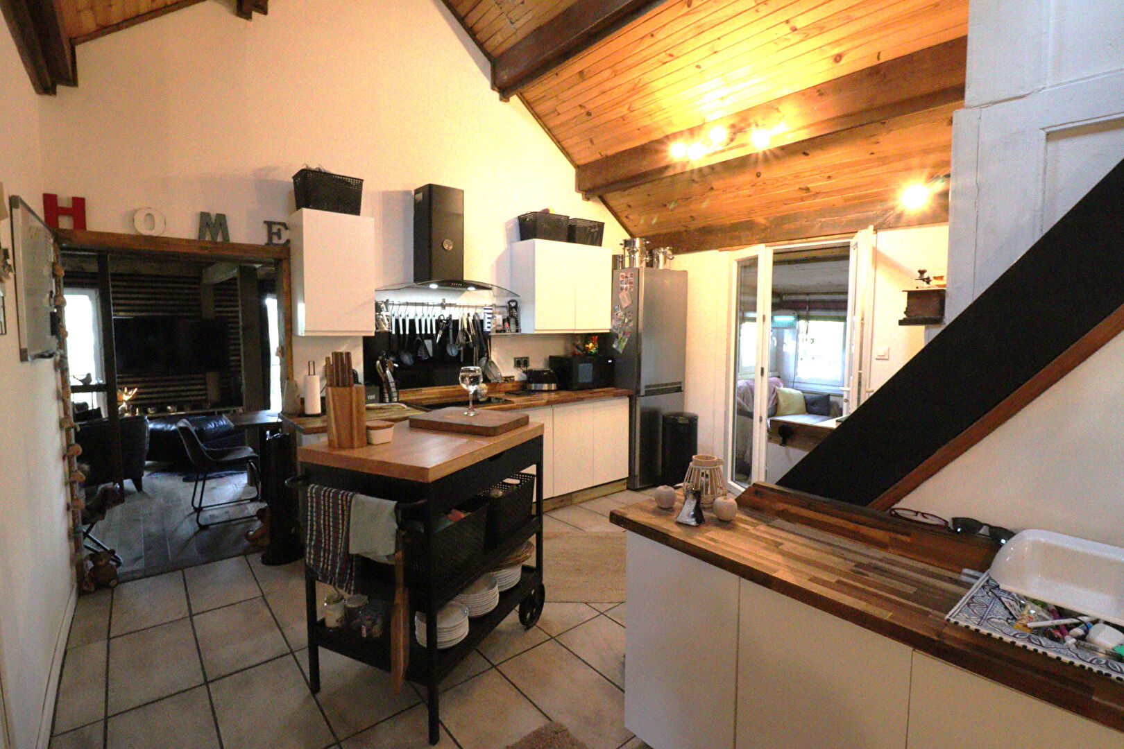 Stylish kitchen with wooden beams, modern appliances, and dining area in a property located in Corrèze, Nouvelle-Aquitaine.