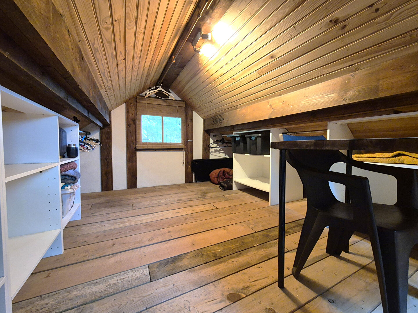 Spacious interior with wooden beams and flooring, featuring storage and a table in a property located in Corrèze