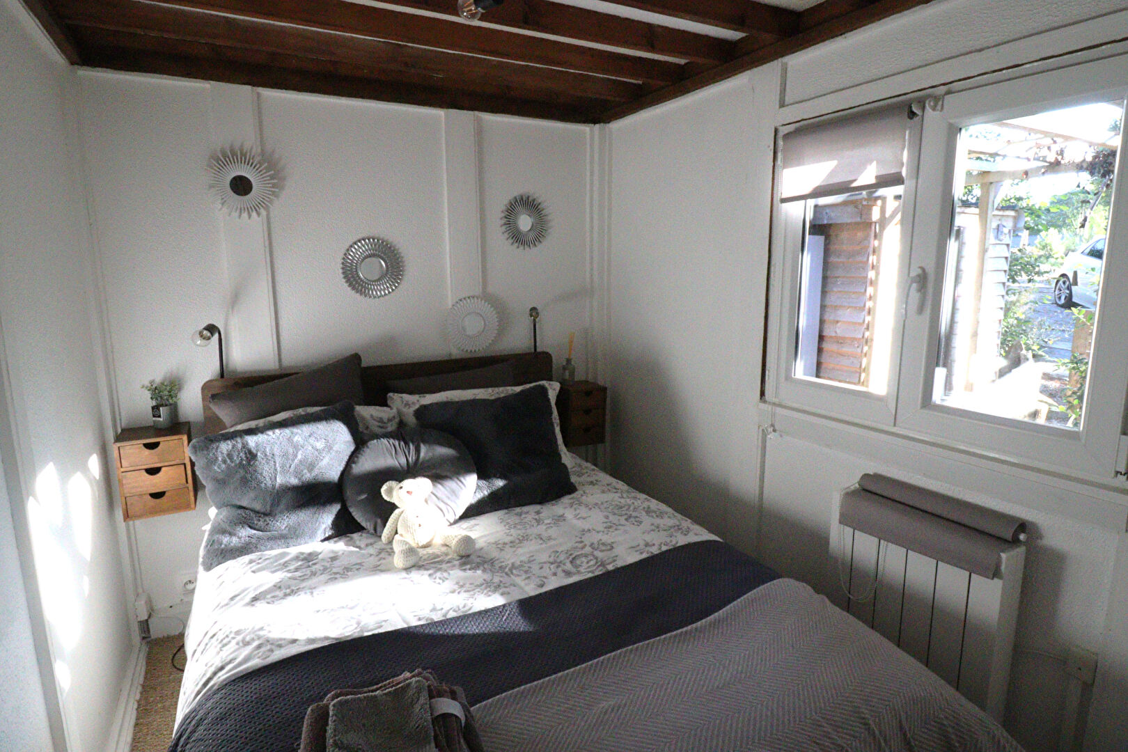 Bright bedroom featuring a double bed, wooden beams, and natural light in Corrèze, Nouvelle-Aquitaine.