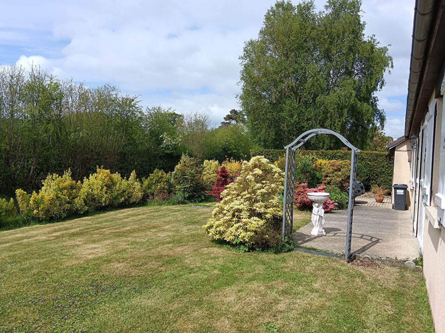 Five-bedroom property with landscaped garden in Manche, Normandy, featuring greenery and outdoor seating area.
