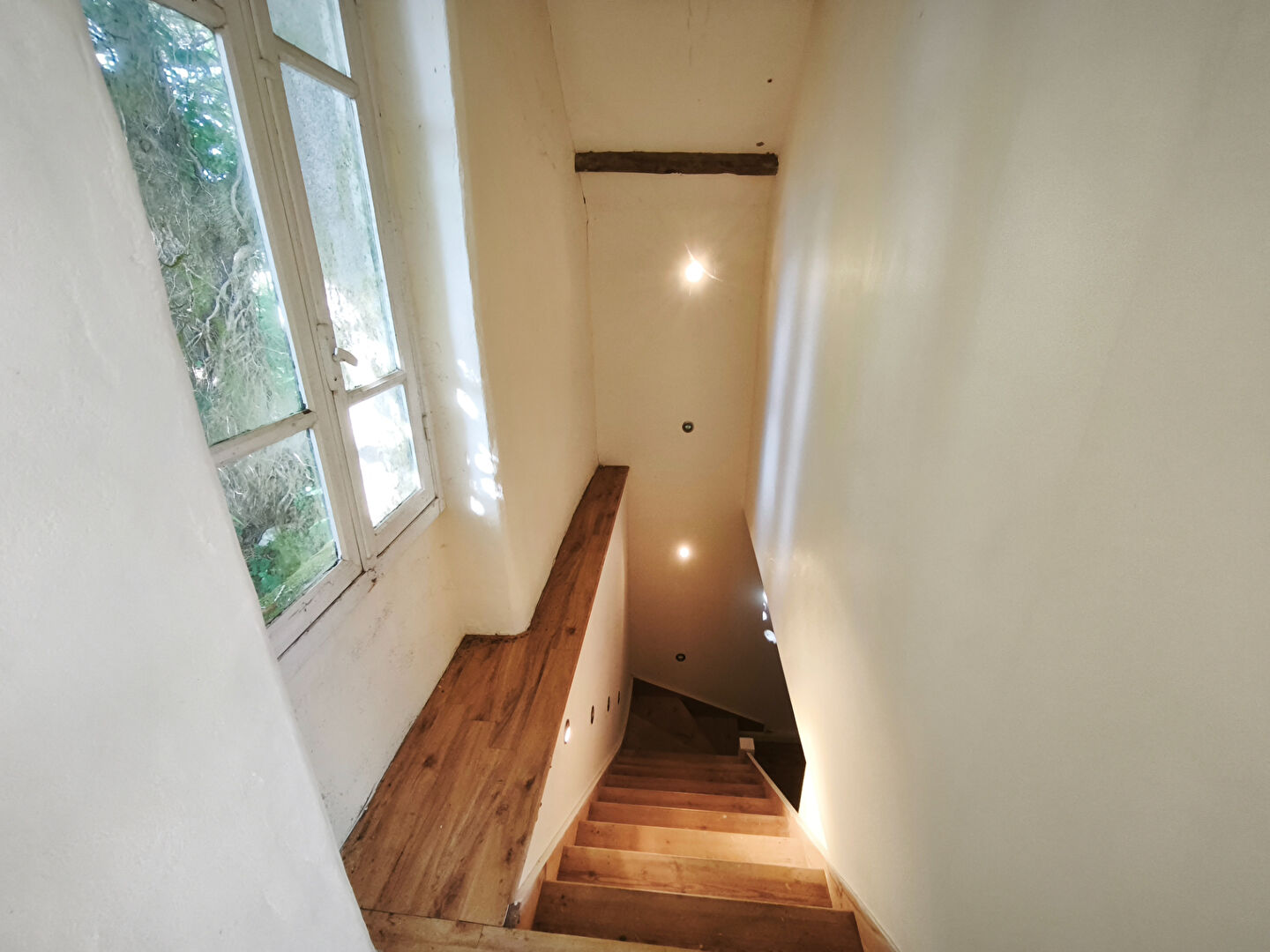 Stairs leading down with wooden steps and window, featuring a property in Morbihan, Brittany with three bedrooms.